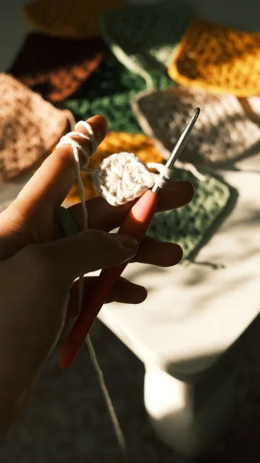 Hands crocheting colorful granny squares